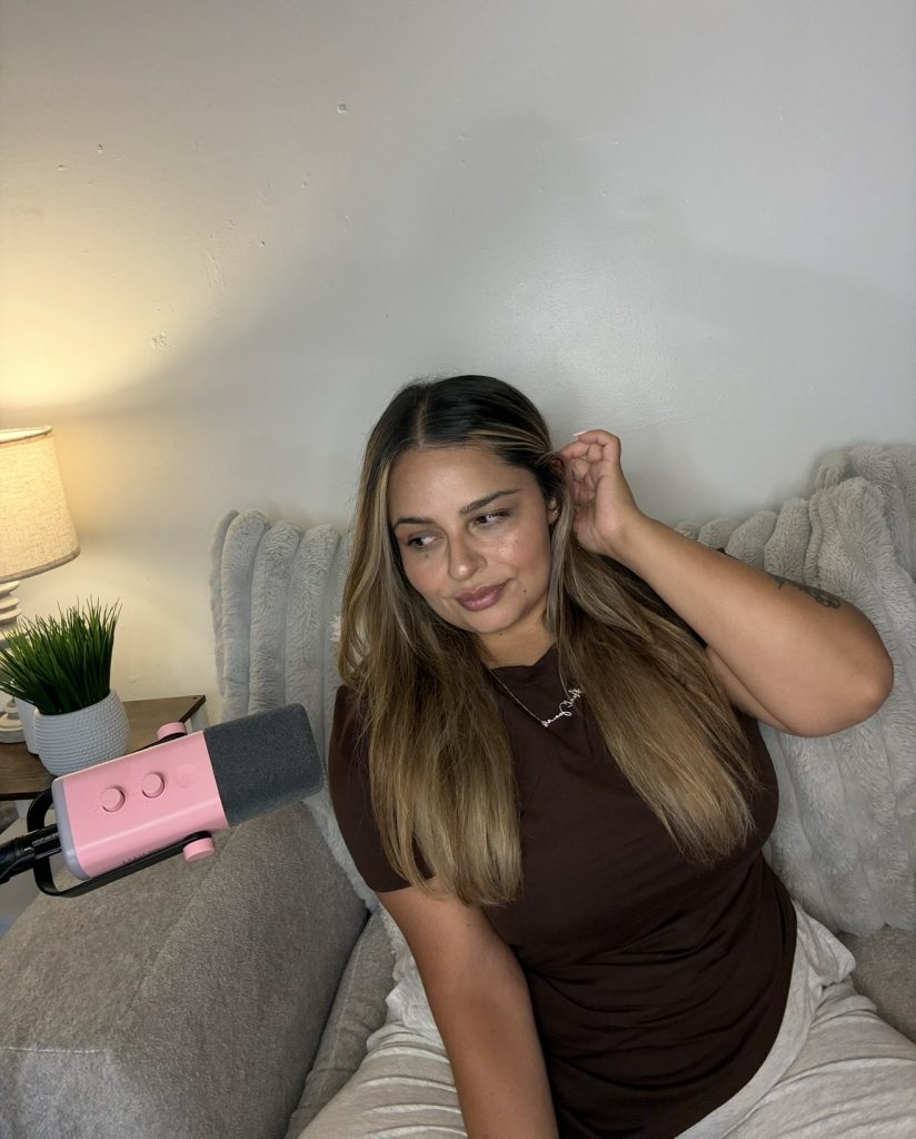 Lex, a SAHM after leaving nursing, sitting on the couch beside the pink microphone she records the Mom Gone Mild Podcast with
