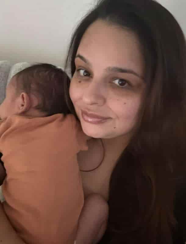 Mom smiling as she holds her sleeping newborn son against her shoulder