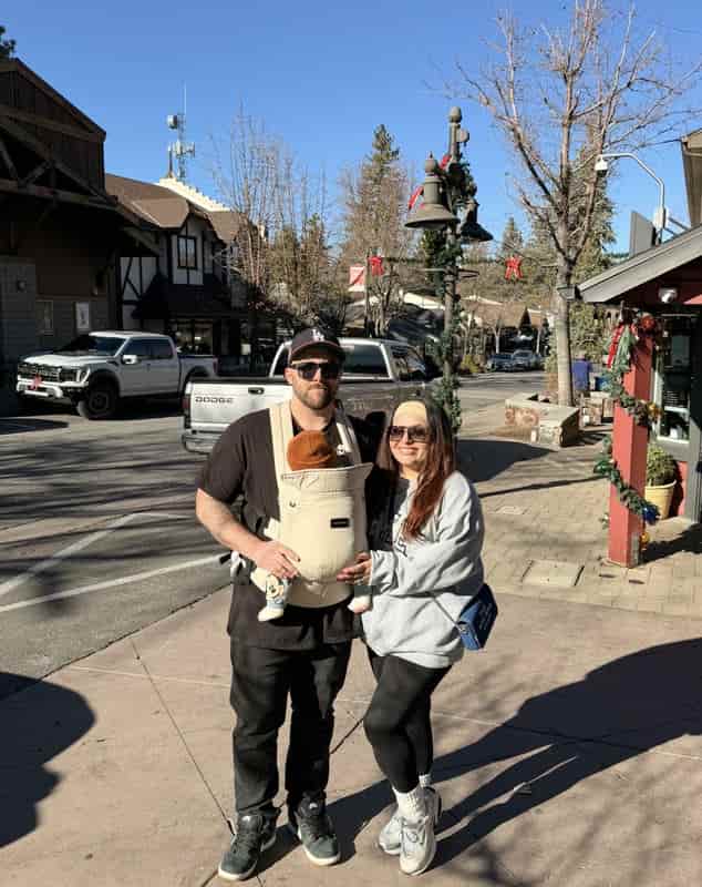 Parents wearing their four-month-old baby in a carrier while walking through Big Bear Village at Christmas