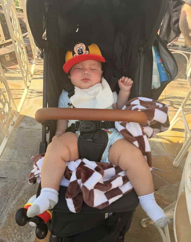 Baby napping in a stroller with Mickey Mouse ears at Disneyland, a favorite thing to do with a baby in Southern California